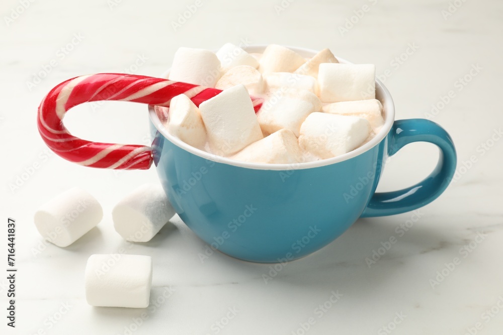 Tasty hot chocolate with marshmallows and candy cane on white marble table, closeup Tasty hot chocolate with marshmallows and candy cane on white marble table, closeup