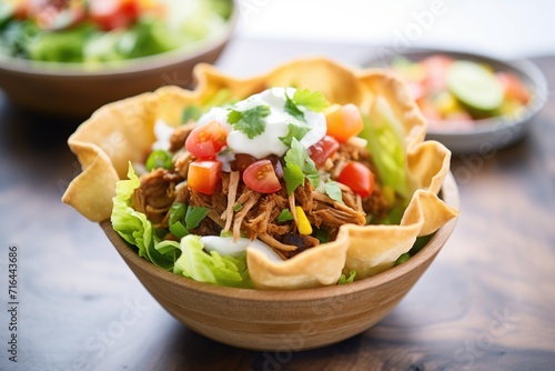 taco salad in a fried tortilla bowl with sour cream