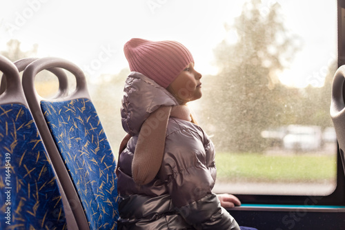 Side view of child girl 5 year old riders on public bus metropolitan transport, looking ahead. Cute little kid girl in trolleybus, city lifestyle. Public urban transport concept. Copy ad text space