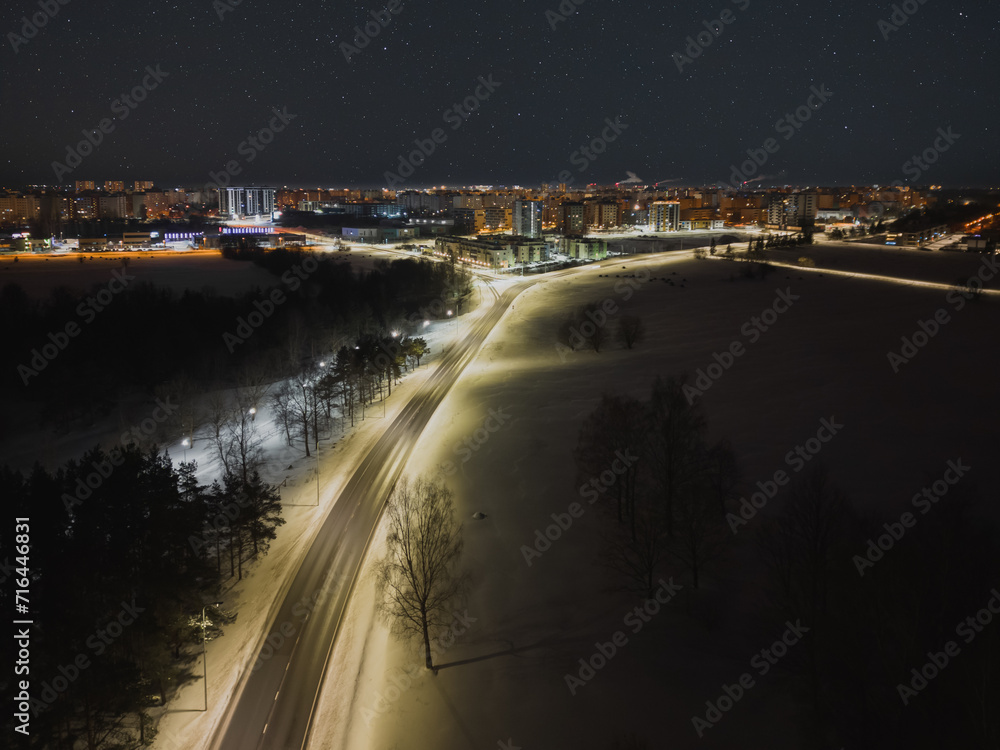Night scene, drone photo. The road leading to the Lasnamae area, the city glows in the dark, starry sky.