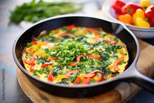 whole veggie omelette in skillet with red and green peppers