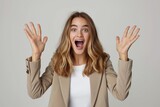 Photo studio shot of a stylish young businesswoman hand rise and yelling, looking very glad and surprised. The background is clean, solid white background.