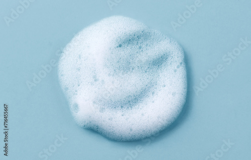 Foam smudge on blue background. Liquid soap bubbles, Froth bubbles backdrop. Drop. Cosmetics soap foam popping bubble. Soap sud macro structure close-up. Clean, cleaning, washing, laundry. Top view. 