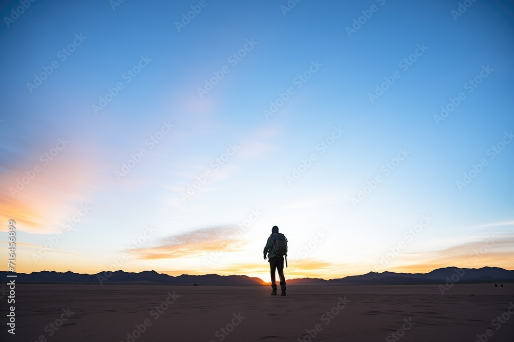 hiker silhouette on vast desert expanse at dusk