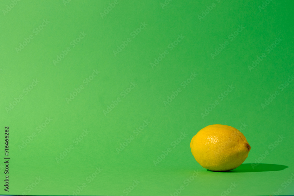 Single lemon citrus fruit against a seamless green background Single lemon citrus fruit against a seamless green background