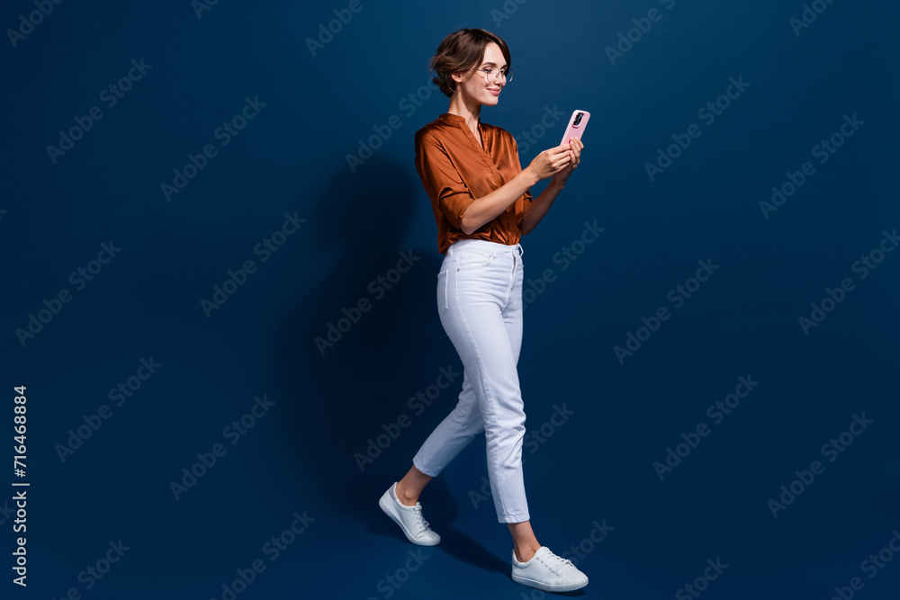 Full length photo of sweet pretty lady wear brown shirt texting apple iphone samsung modern gadget isolated blue color background