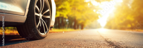 Close up tire and wheel of a car on the road in background. The driving concept of travel and vacation.