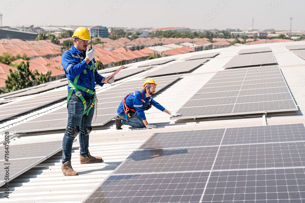 Men technicians carrying photovoltaic solar modules on the factory roof