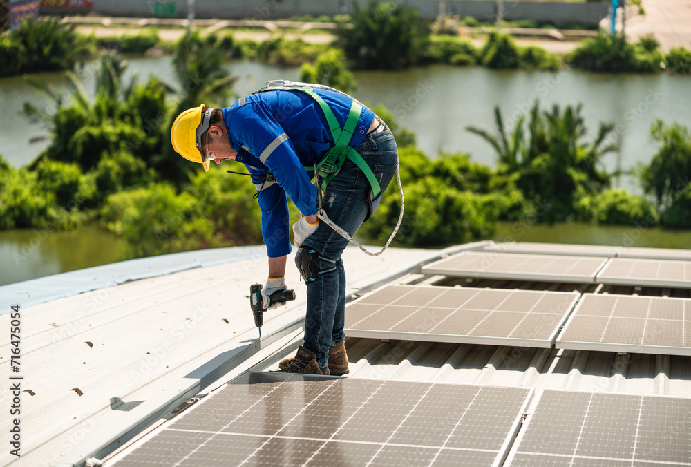 Men technicians carrying photovoltaic solar modules on the factory roof. Engineers in helmets installing solar panel systems outdoors. Concept of alternative and renewable energy solar cell. Men technicians carrying photovoltaic solar modules on the factory roof. Engineers in helmets installing solar panel systems outdoors. Concept of alternative and renewable energy solar cell.