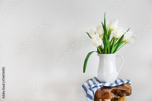 Tulips bouquet in white vase on wooden rustic chair