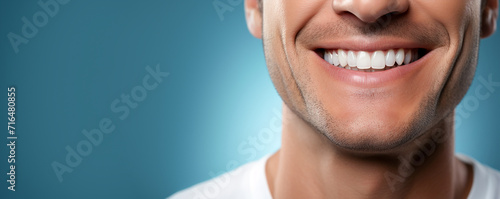 Close-up of a smiling man's mouth with clean, healthy teeth. Teeth whitening. Dentistry. Blue background, copy space, banner