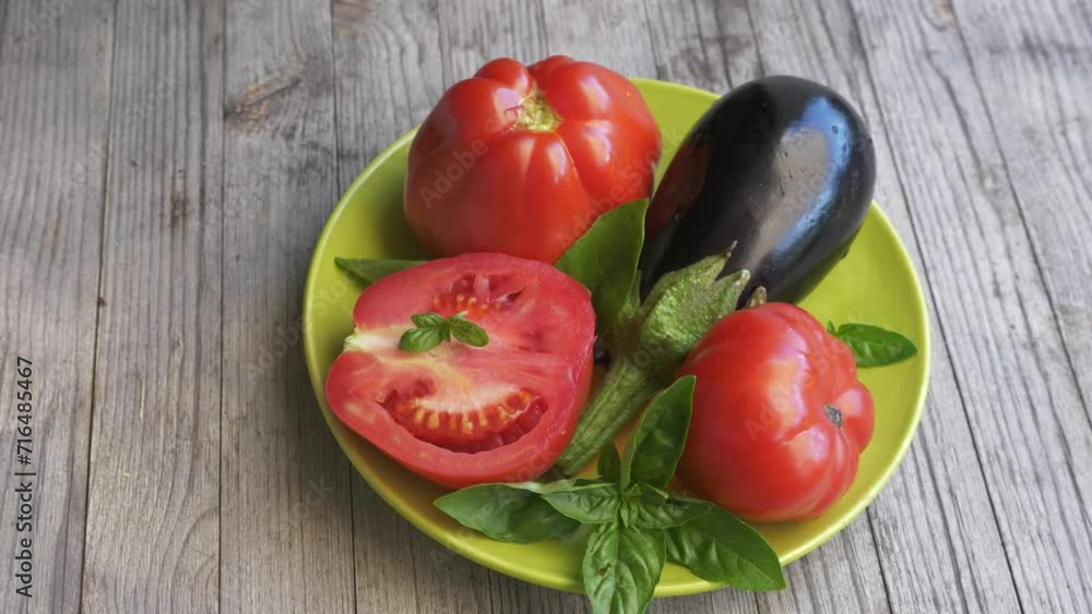 Tomatoes, an eggplant and basil on a plate Tomatoes, an eggplant and basil on a plate