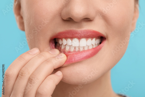 Woman showing her clean teeth on light blue background, closeup