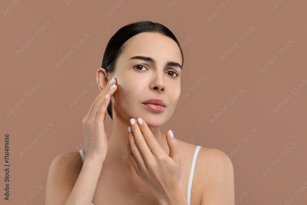 Woman with dry skin checking her face on beige background, space for text