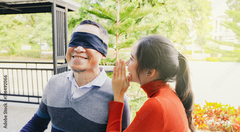 Obraz premium Grateful daughter beautiful eldest daughter covered her eyes with black cloth surprise your retired old man and whisper sweet words into his ear by buying him new house as a gift.