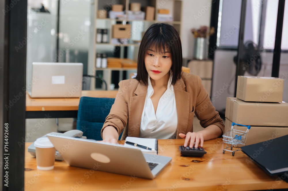 Young business owner woman prepare parcel box and standing check online orders for deliver to customer on tablet, laptop Shopping Online.. Young business owner woman prepare parcel box and standing check online orders for deliver to customer on tablet, laptop Shopping Online..