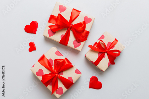 Top view photo of valentine day decorations gift box with red ribbon bow on colored background. Holiday gift boxes with top view