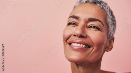 A happy senior lady showcasing stylish grey hair and smiling against a studio backdrop.