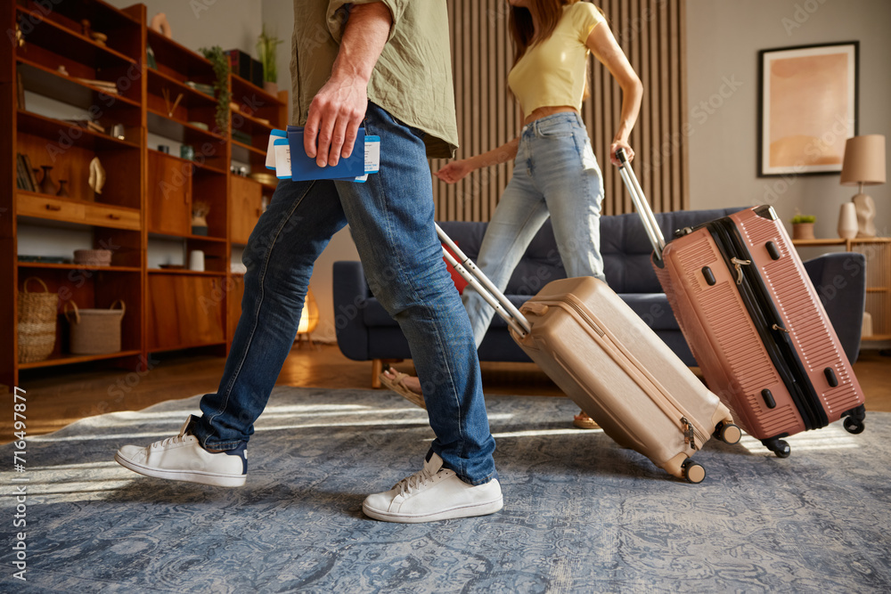 Closeup man and woman walking with luggage leaving home