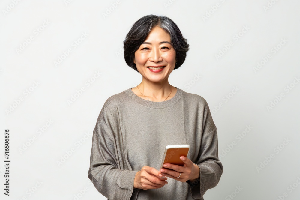 Smiling mature asian woman with a smartphone isolated on a white background Smiling mature asian woman with a smartphone isolated on a white background
