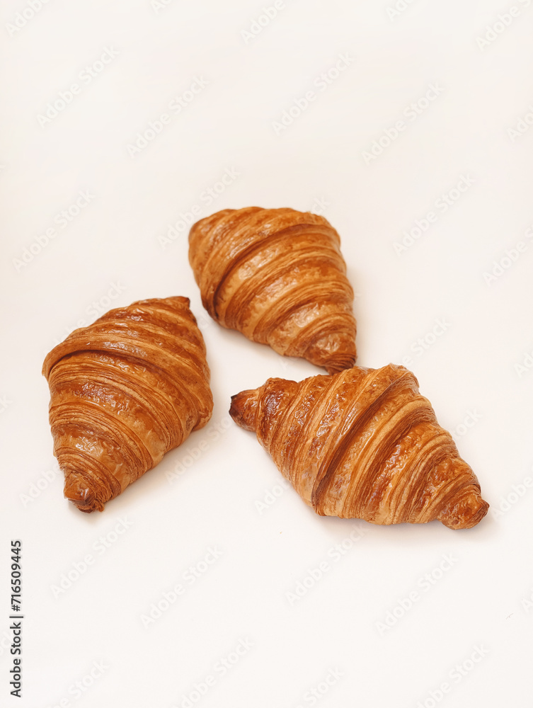 Fresh 3 French croissants with shadows on white background and space for text.
