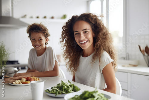 Warm mother-daughter moment in a bright kitchen  with healthy food on the table  both smiling and enjoying each other   s company