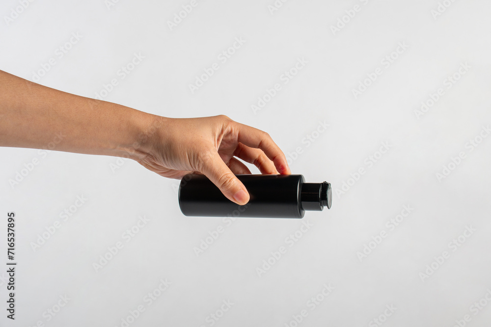 Black cosmetic bottle in hand isolated on white background. Black cosmetic bottle in hand isolated on white background.