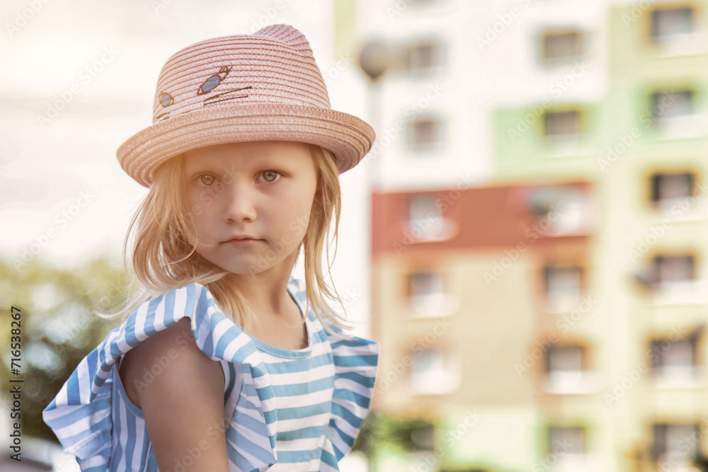 Portrait of cute 4 year little girl in summer hat in summer park outdoors, looking at camera.