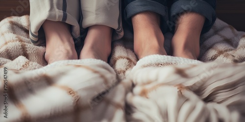 Two pairs of feet sticking out from under cozy blankets , Two pairs of feet, cozy blankets