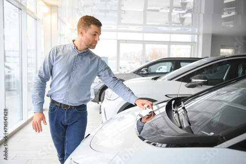 A young man chooses a new car at a car dealership.