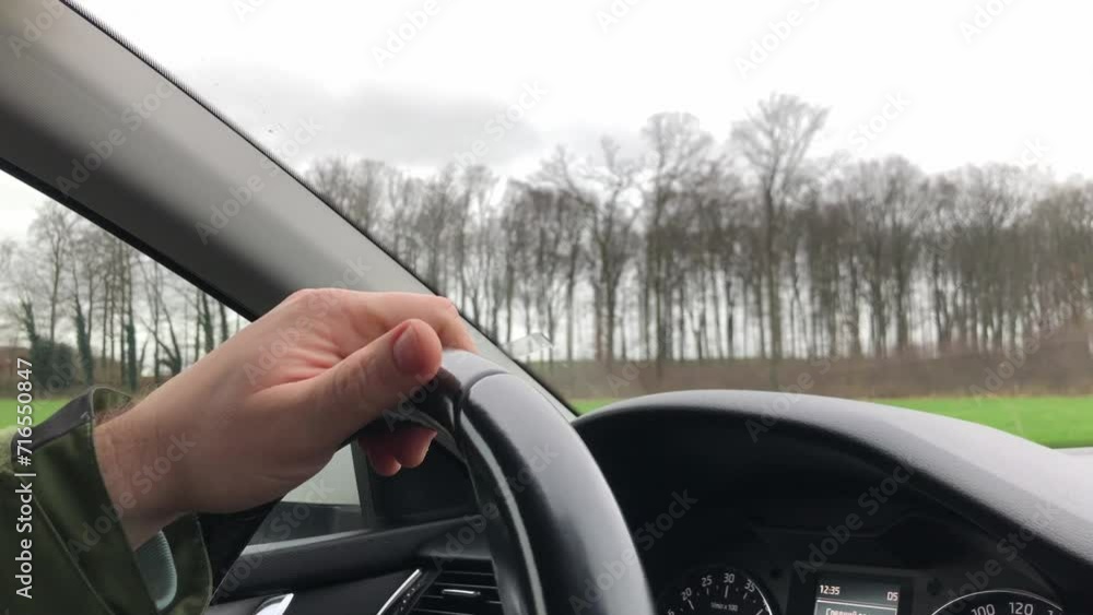 The driver's hand on the steering wheel against the background of the road during the day. Close-up. 4K. High quality video The driver's hand on the steering wheel against the background of the road during the day. Close-up. 4K. High quality video