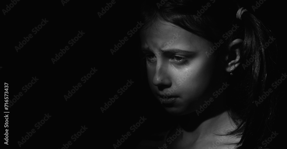 Black and white image of crying young girl. Loneliness, pain, child tragedy. Copy space for text or design.