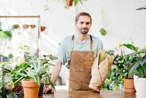 Handsome Caucasian salesman, employee selling potted plants in a flower store.