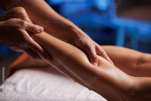 Male masseurs hands press female visitors leg, relaxing massage in spa salon. Body care for young woman.Therapeutic procedure for an injured leg, restoration of health.
