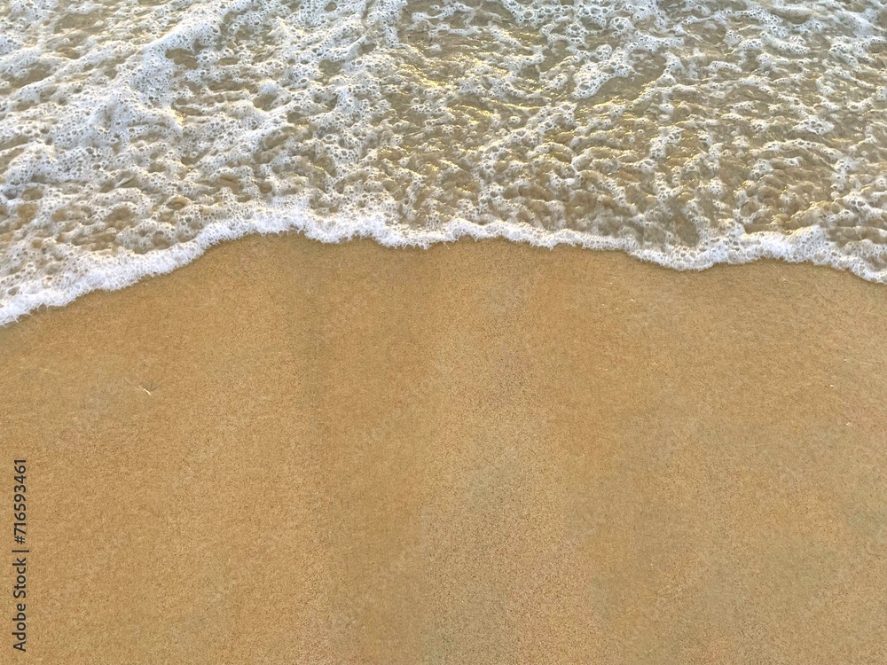 sunny Small, Soft wave on sand beach, text copy space for banners, cards. Close up top view of sea blue waves break on sand. photo was shot in evening at sunset sunny Small, Soft wave on sand beach, text copy space for banners, cards. Close up top view of sea blue waves break on sand. photo was shot in evening at sunset