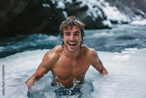 young happy man bathes in winter in an icy river in nature