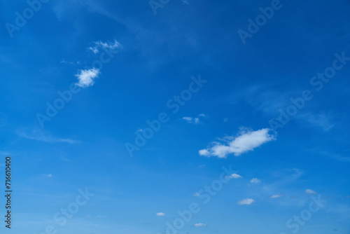 Clear blue sky background with small white fluffy clouds