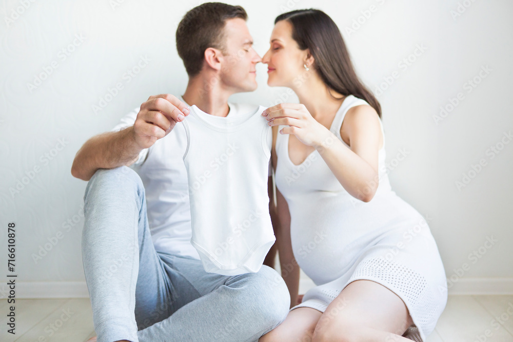 Young man and pretty pregnant woman with baby wear Young man and pretty pregnant woman with baby wear