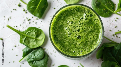 Fresh green smoothie next to raw spinach leaves on a white surface, concept of detox and clean eating photo