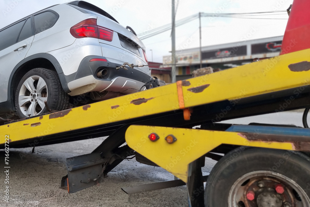 Closeup of flat bed tow truck attempt to tow and rescue broken down car Closeup of flat bed tow truck attempt to tow and rescue broken down car