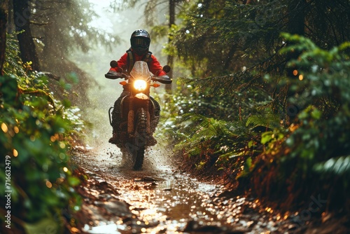 Motorcyclist riding on a dirt road in the rain forest. Motocross. Enduro. Extreme sport concept. photo