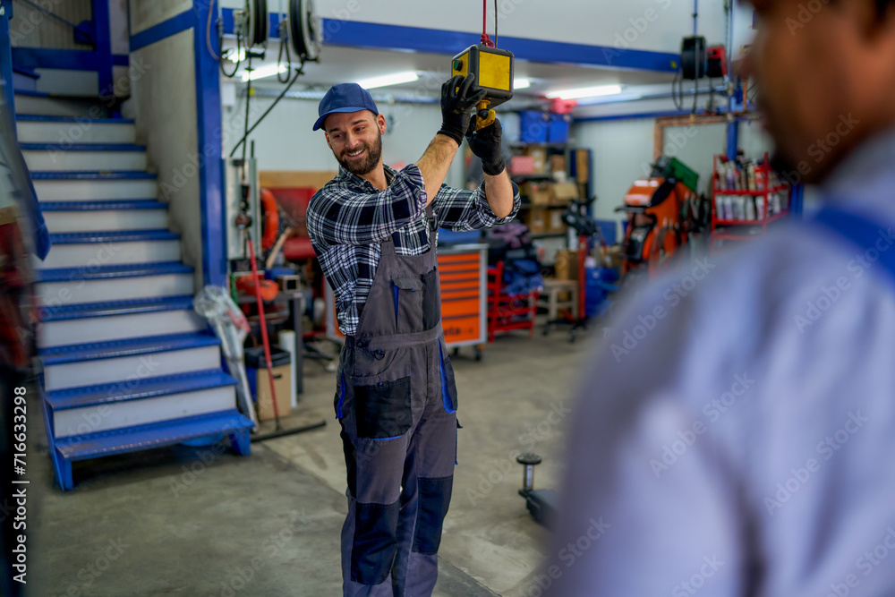 A skilled mechanic takes control, managing the workshop's car lift with precision. A skilled mechanic takes control, managing the workshop's car lift with precision.