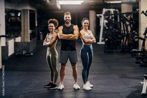 Portrait of muscular sportspeople in shape posing in a gym while smiling at the camera.