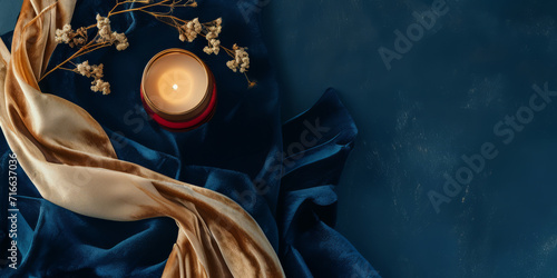 Elegant dark blue textile background with a lit candle and golden fabric, suitable for luxury and calm themes