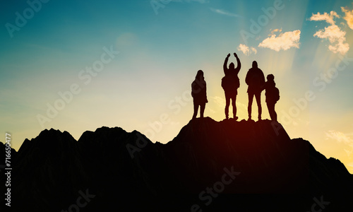 Hiking family Silhouette on top of mountain against sunset. Happy People Standing on too hill. Copy space. 