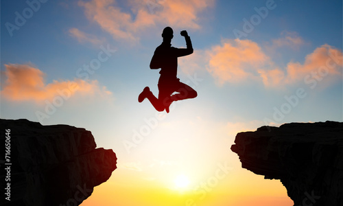 Silhouette of a man jumps over Clif gap. Challenge and happiness. 