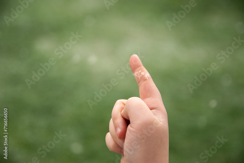 Girls open hand with snowflake on finger. Green natural background. © Iryna