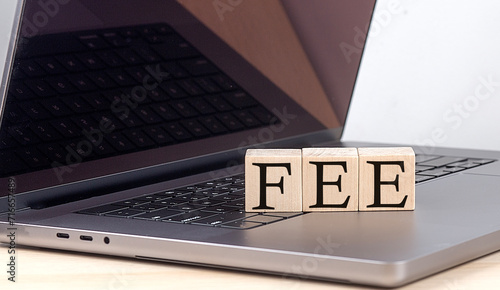 FEE word on wooden block on laptop, business concept