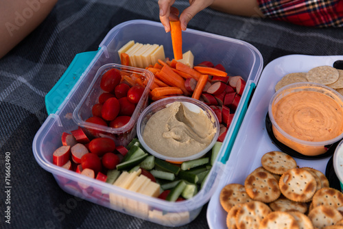 food in containers on a picnic rug in a park photo