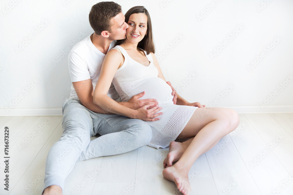 Young man and pretty pregnant woman hugging together Young man and pretty pregnant woman hugging together